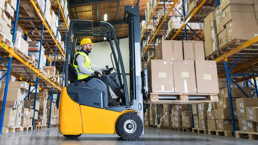 A forklift driver working in a busy warehouse